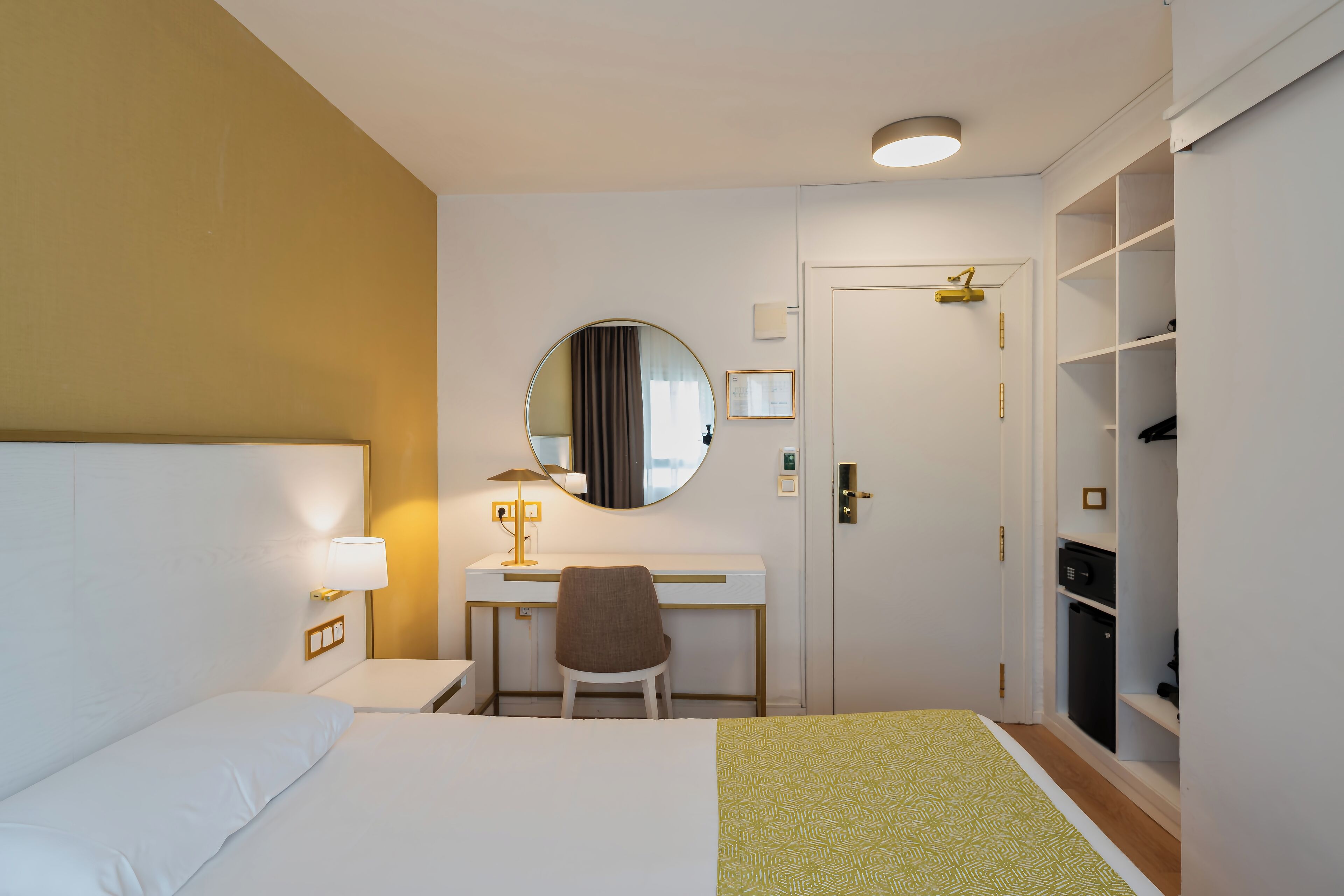 Ein Hotelzimmer mit Bett, Schreibtisch, Stuhl und Kleiderschrank.