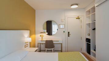 Ein Hotelzimmer mit Bett, Schreibtisch, Stuhl und Kleiderschrank.