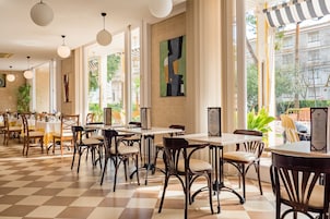 Un grand espace dédié à la salle à manger, avec un sol à carreaux, des tables et des chaises en bois.