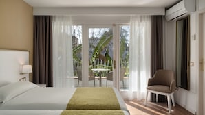 A hotel room with two beds, a chair, a table, and a view of the outdoors. - Hotel Araxa - Adults Only (Palma de Mallorca)