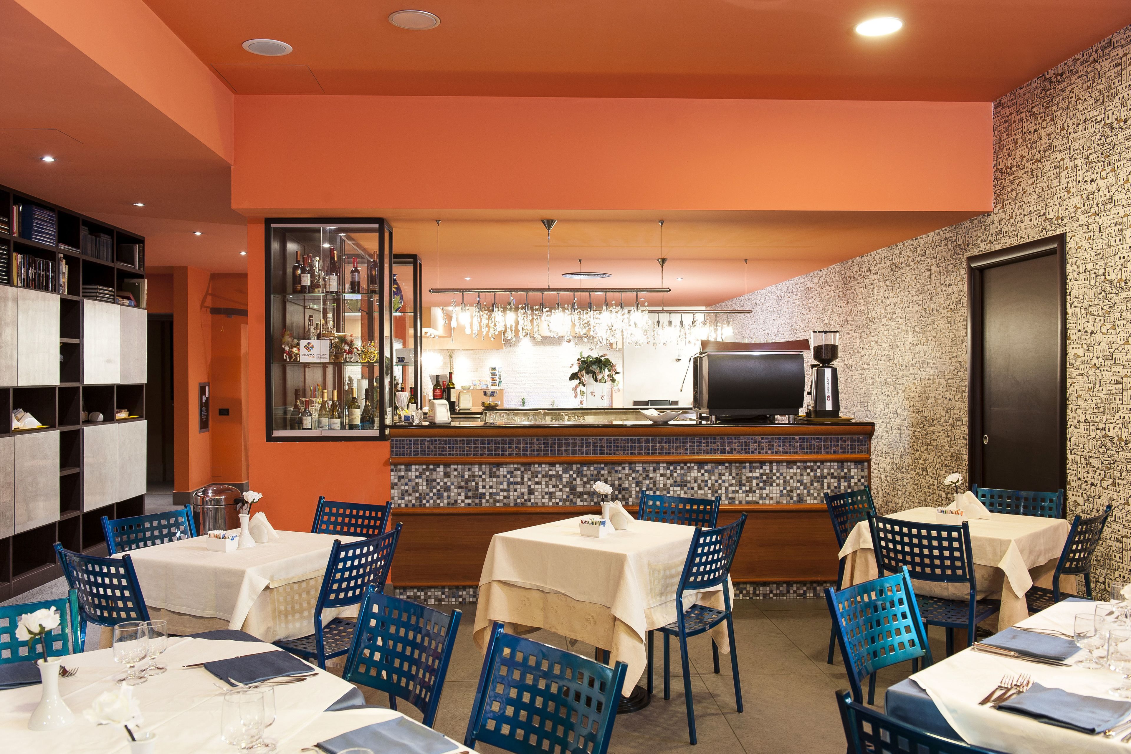 En restaurant med borde, stole, en bar og et køkken i baggrunden.