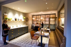 A modern kitchen with grey cabinets, a central island, and a dining area with a bench and table. - The Orchid Hotel (Bournemouth)