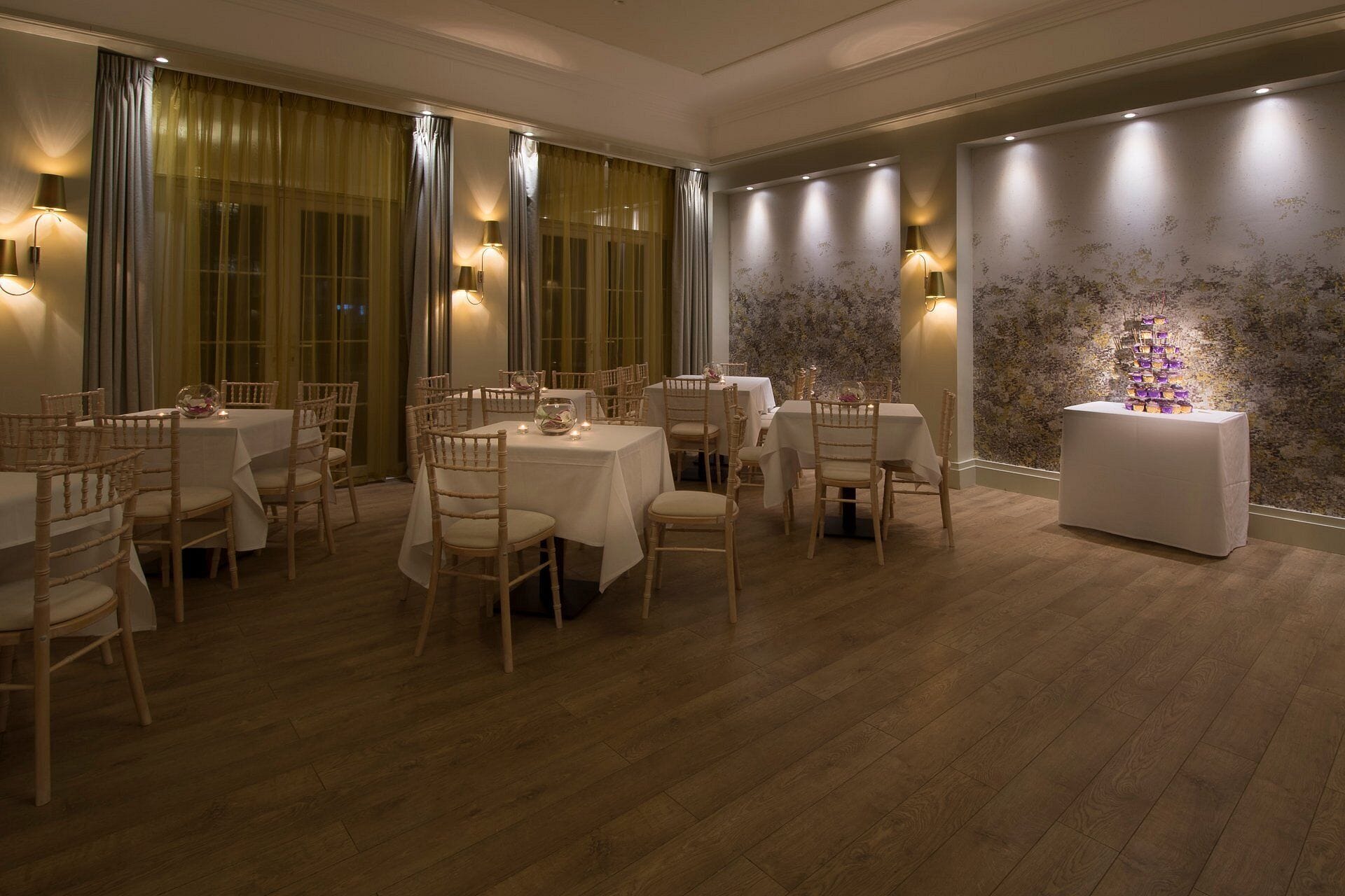 A dining area with multiple tables and chairs, warm lighting, and a decorative wall.