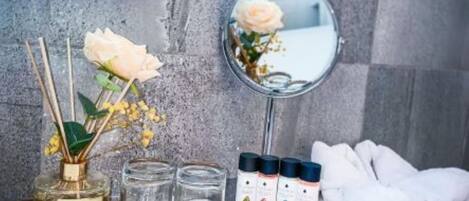 Un meuble-lavabo de salle de bain avec un miroir, un plateau contenant un flacon de liquide, un verre et une petite boîte.