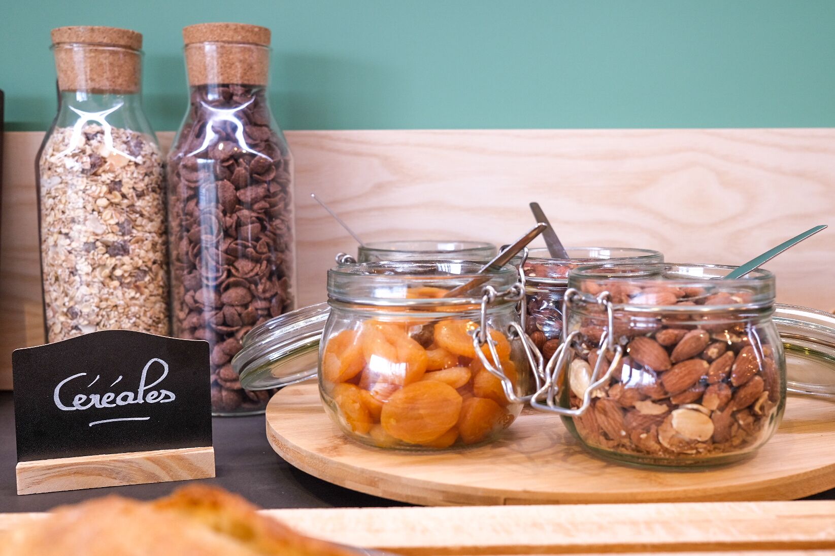 Three glass jars with metal clasps containing different types of nuts and dried fruits on a wooden board.