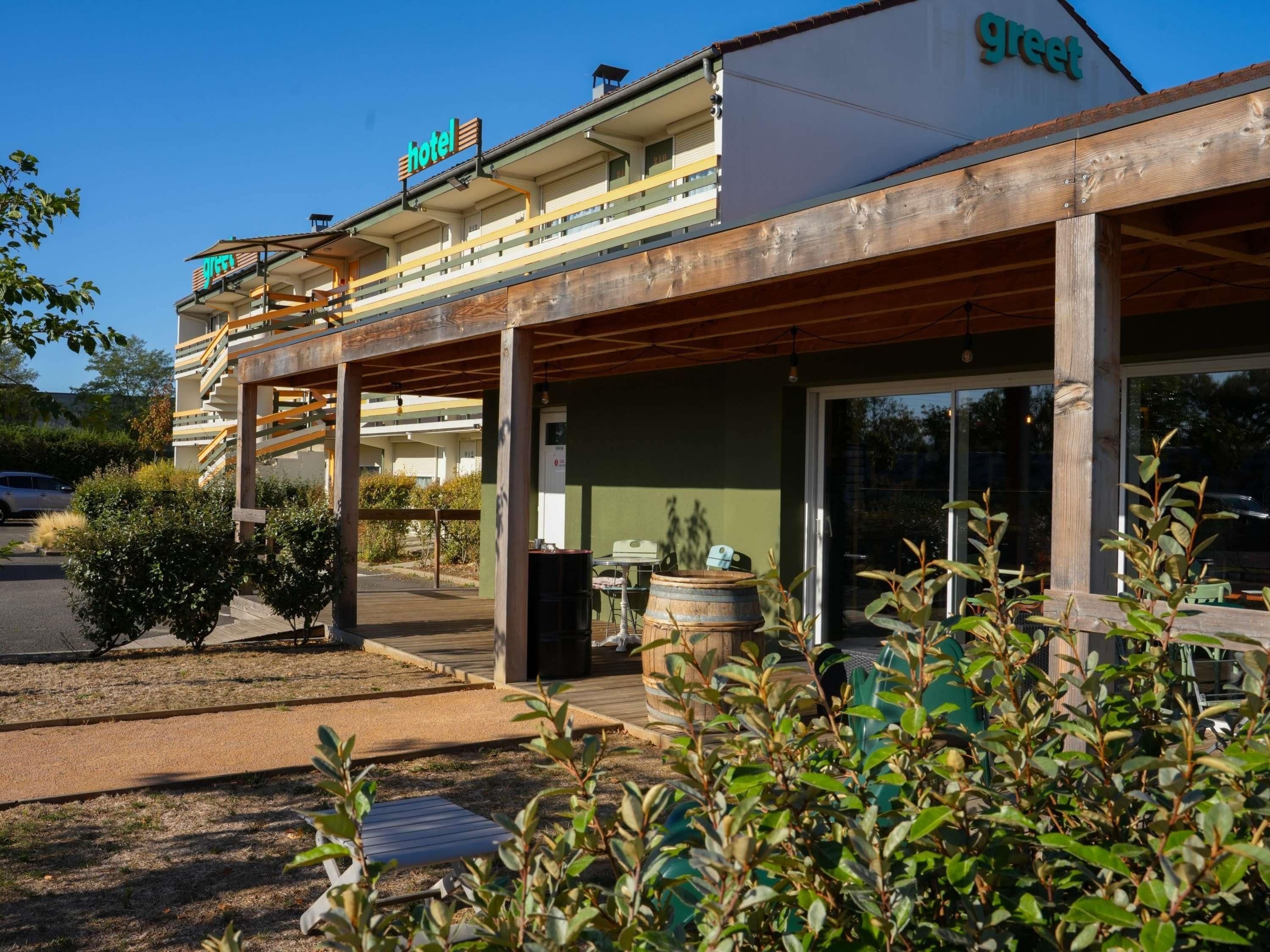A hotel with a covered outdoor area, a barbecue setup, and a view of the surrounding greenery.