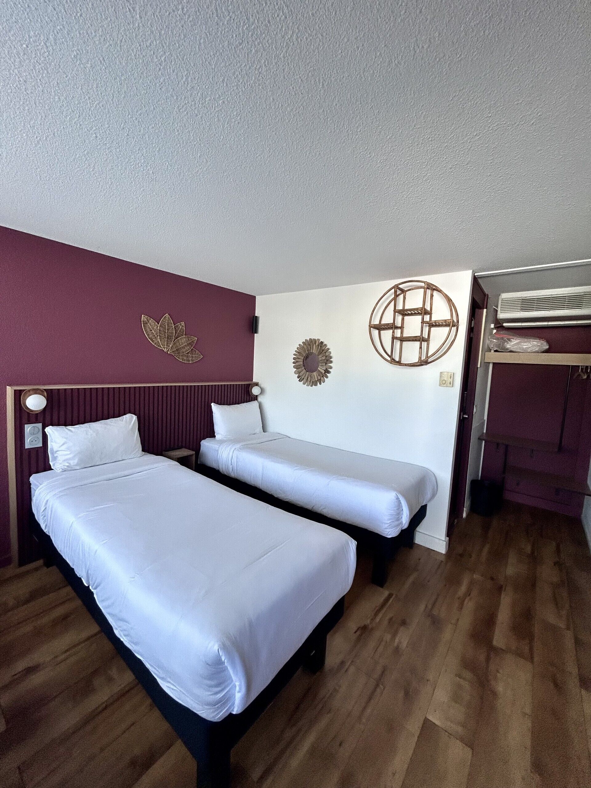 Une chambre avec deux lits, une horloge murale et un élément décoratif circulaire fixé au mur.