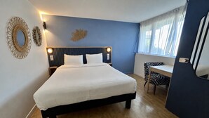A bedroom with a bed, bedside lamps, a desk, and a chair.