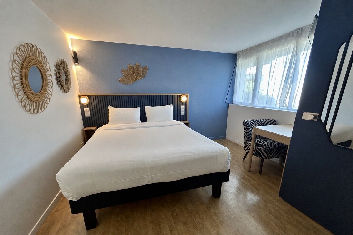 Een slaapkamer met een bed, bedlampen, een bureau en een stoel.