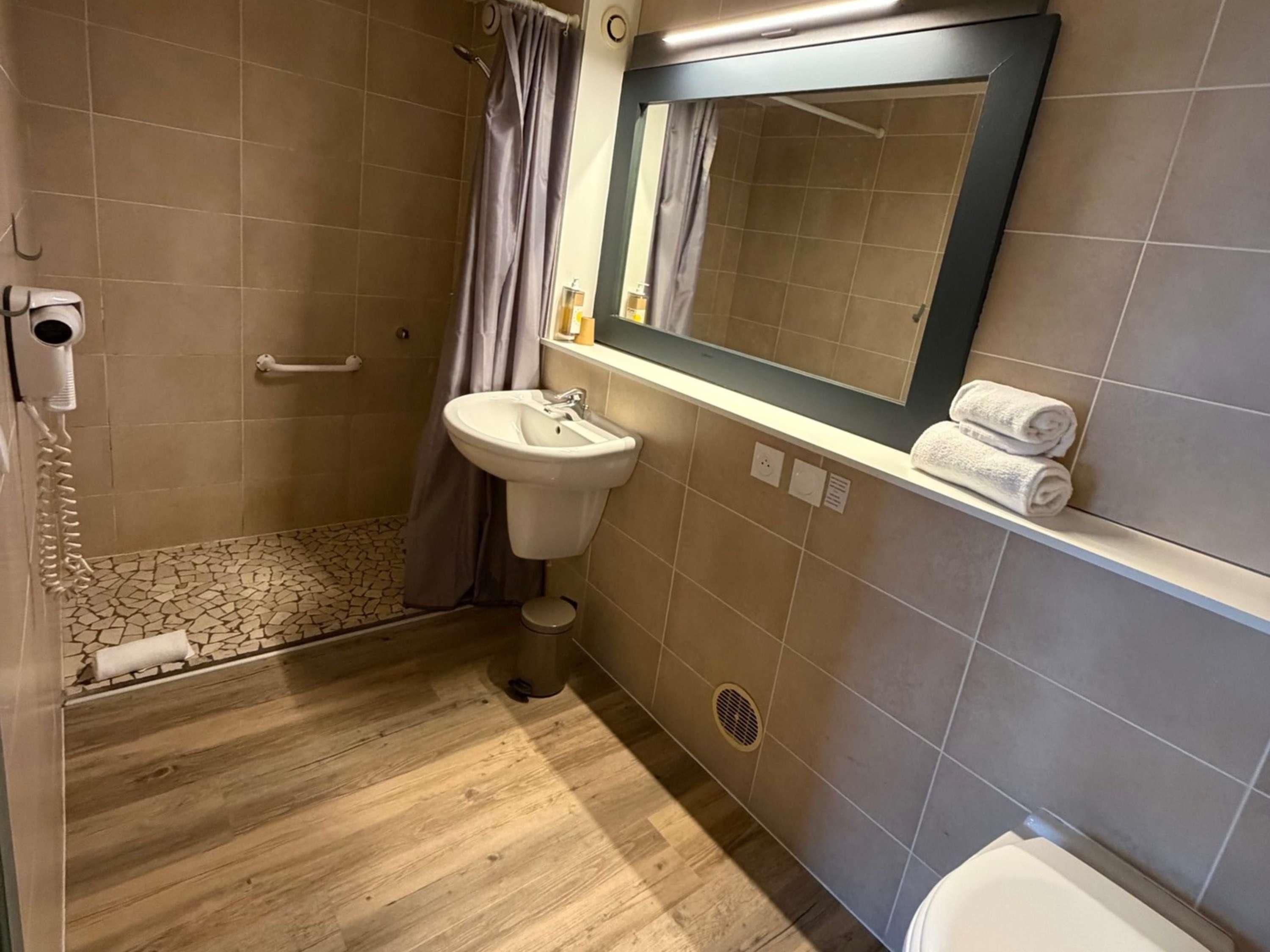 A bathroom with a shower, sink, and toilet.