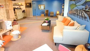 Un hall d’hôtel moderne avec un comptoir d’accueil, un espace salon et une fresque murale.