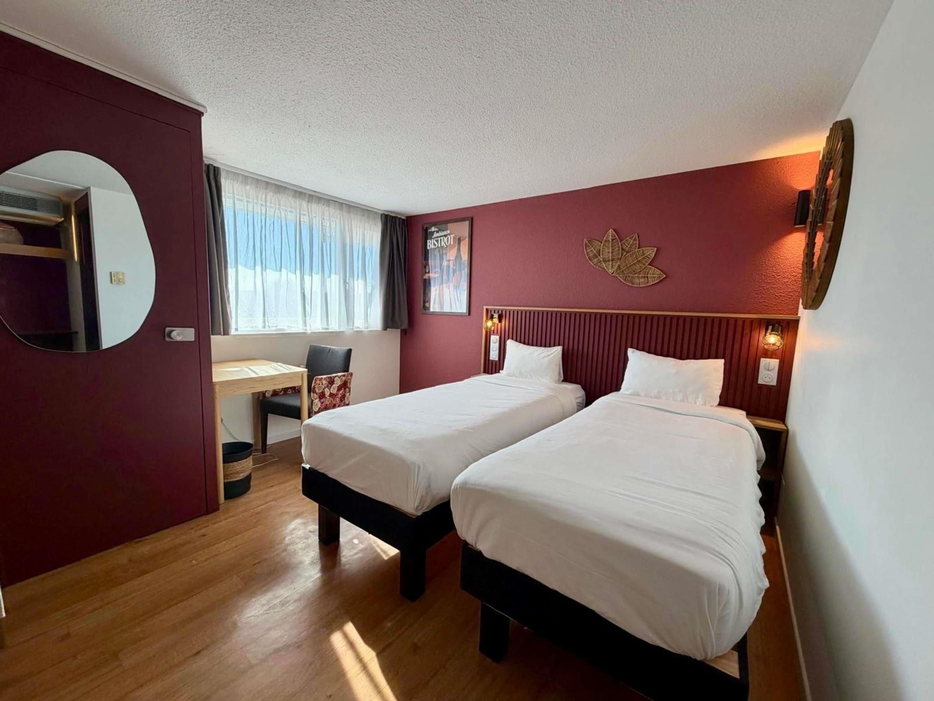 Une chambre d’hôtel avec deux lits, un bureau et une chaise.