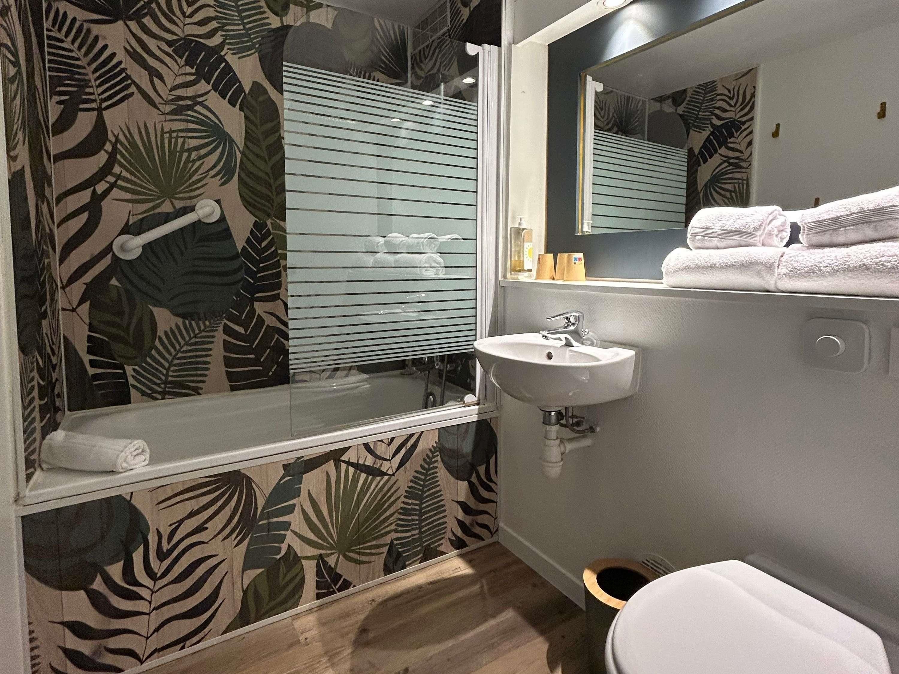 A bathroom with a glass shower enclosure, a white sink, and a toilet.