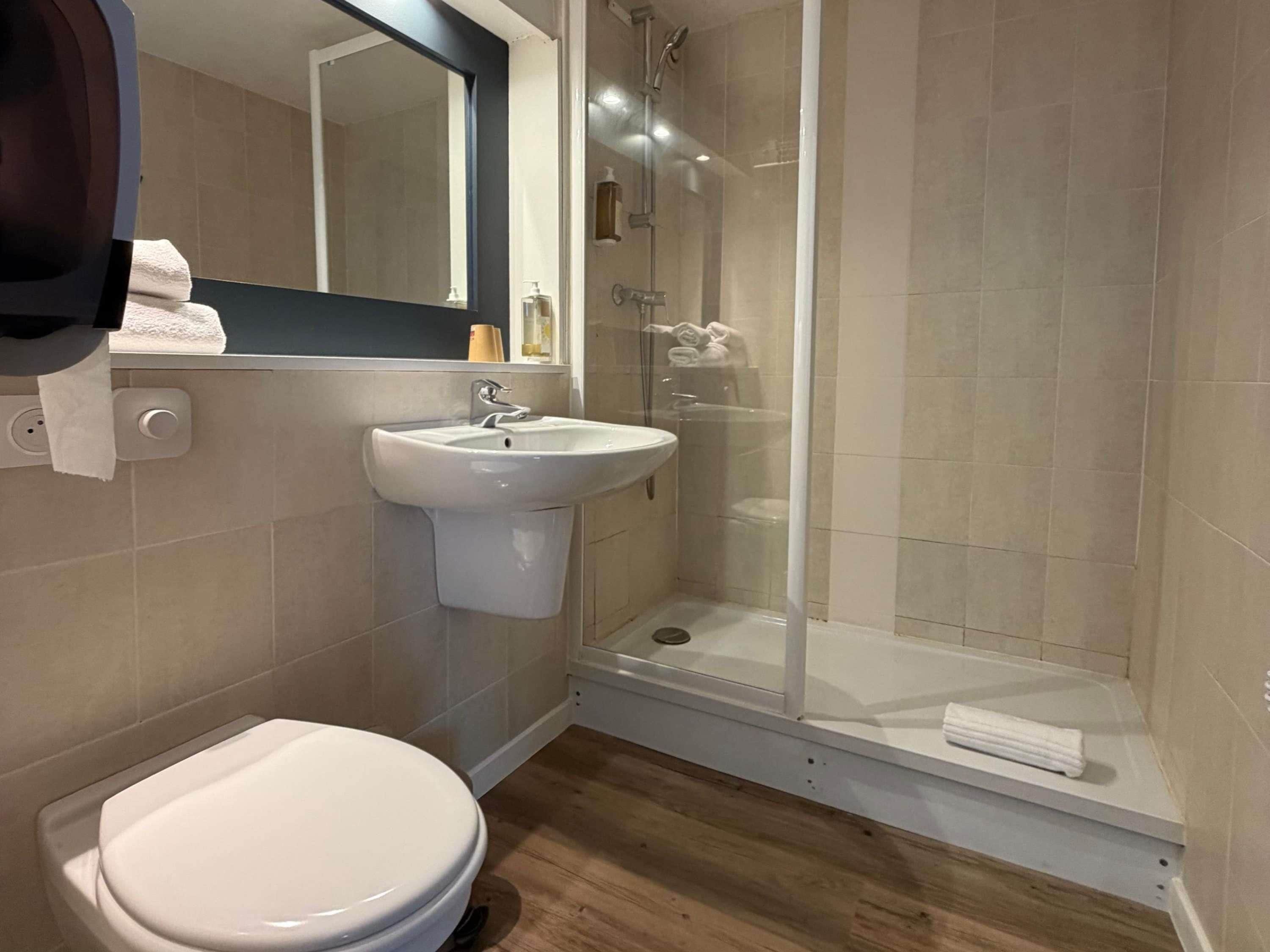 A bathroom with a toilet, sink, and glass-enclosed shower.