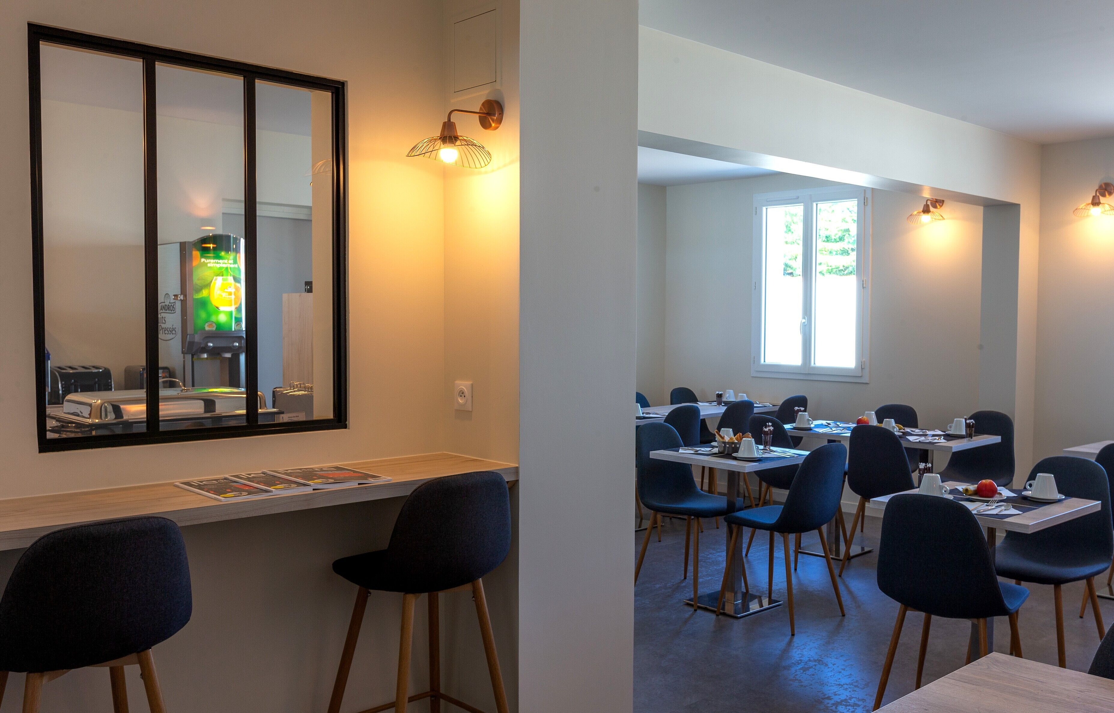 A modern dining area with high tables and chairs, a large mirror, and a vending machine.