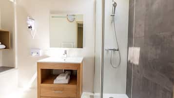 A modern bathroom with a glass-enclosed shower, a wooden vanity, and a large mirror.