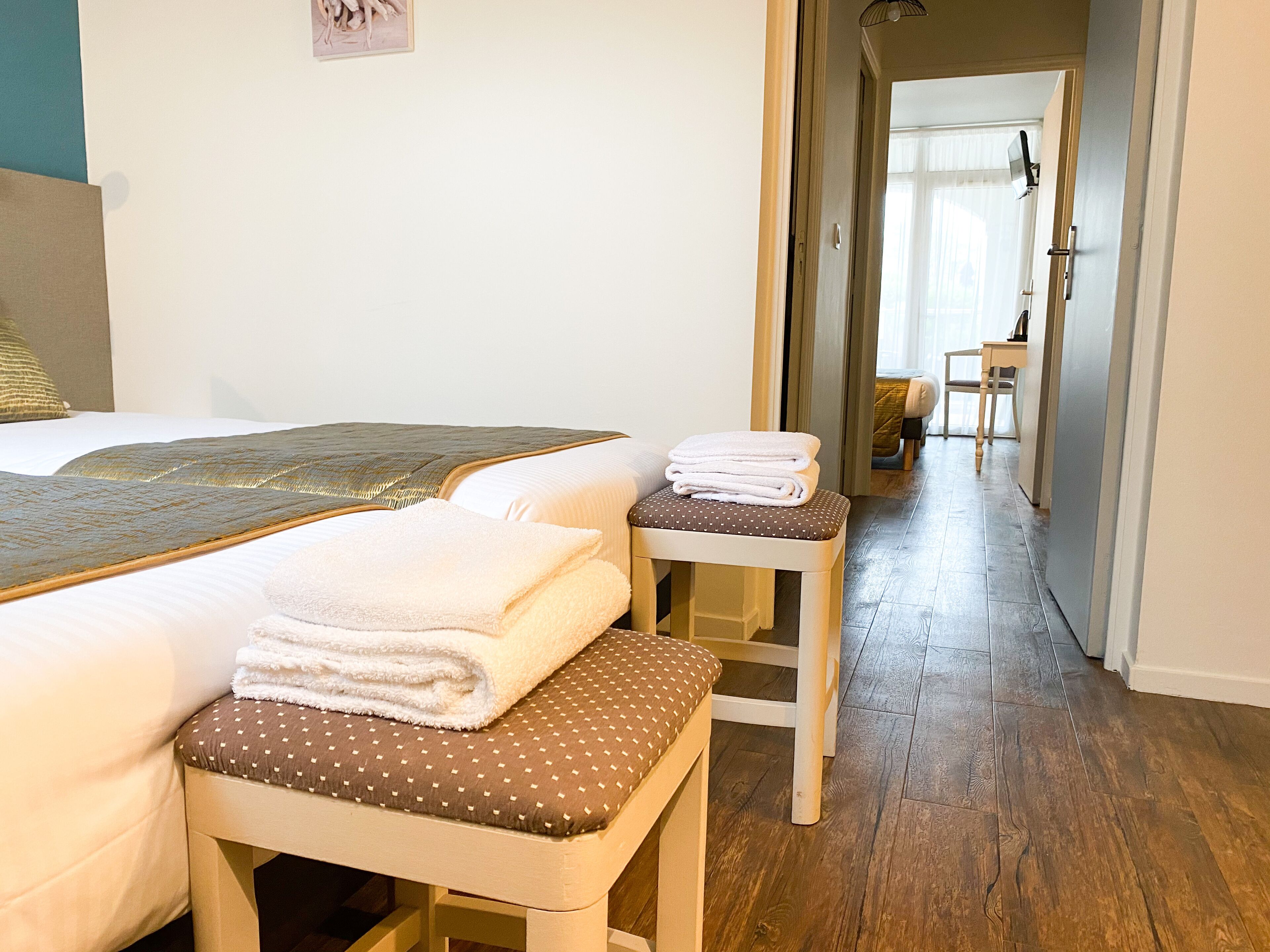 Ein Hotelzimmer mit zwei Betten, einem kleinen Tisch mit Handtüchern und Holzboden.
