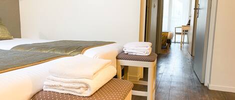 Ein Hotelzimmer mit zwei Betten, einem kleinen Tisch mit Handtüchern und Holzboden.
