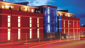 Un hotel moderno con fachada roja, una imponente torre de cristal y una entrada bien iluminada.