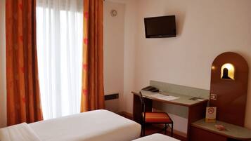 A hotel room with two beds, a desk with a chair, a television, and a desk lamp.