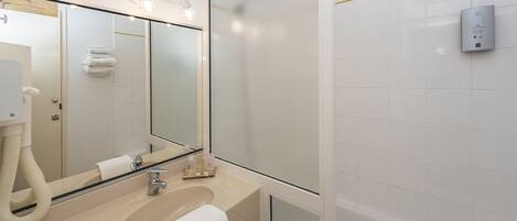 A modern bathroom with a large mirror, a sink, and a shower area.