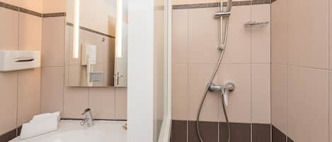Un baño moderno con lavamanos, espejo y ducha.