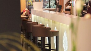 Una moderna zona de recepción con un mostrador blanco, lámparas colgantes rojas y vistas al exterior a través de amplios ventanales.