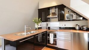 Une cuisine moderne avec un plan de travail en bois, des appareils en acier inoxydable et un pare-feu noir.