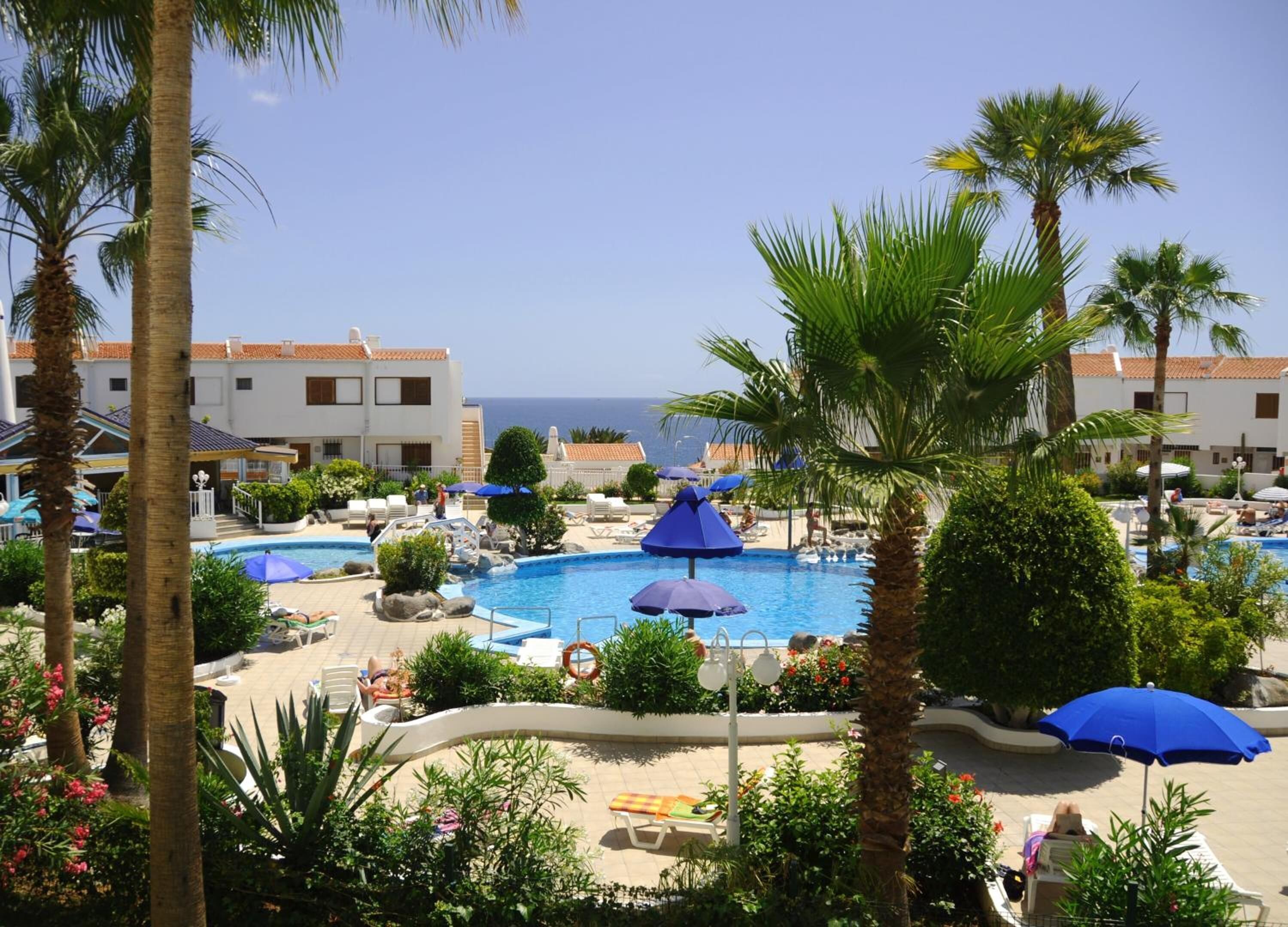 A resort pool area with multiple pools, palm trees, and lounge chairs.
