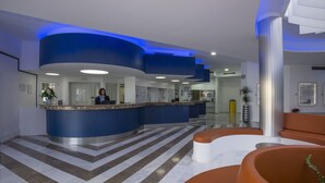 A modern hotel lobby with a reception desk, a staircase, and seating areas. - Hovima Atlantis (Adeje)