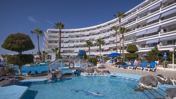 A hotel with a swimming pool, palm trees, and lounge chairs. - Hovima Atlantis (Adeje)