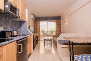 A compact kitchen with a microwave, kettle, and dishwasher. There is a small dining area with a table and chairs. - HOVIMA Santa María (Adeje)