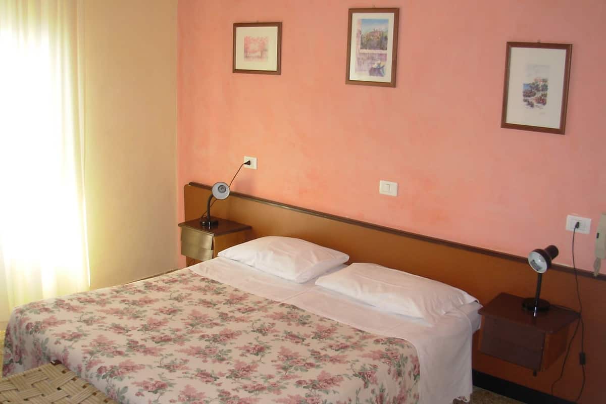 A bedroom with a bed, a nightstand, a lamp, and two framed pictures on the wall.