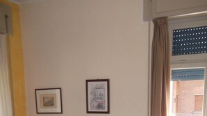 A room with two beds, a chair, and two framed pictures on the wall. - Delle Rose (Torri del Benaco)