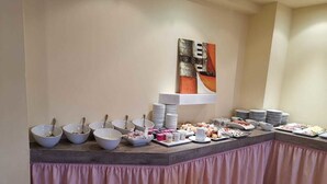A buffet setup with bowls, plates, and various food items. - Delle Rose (Torri del Benaco)