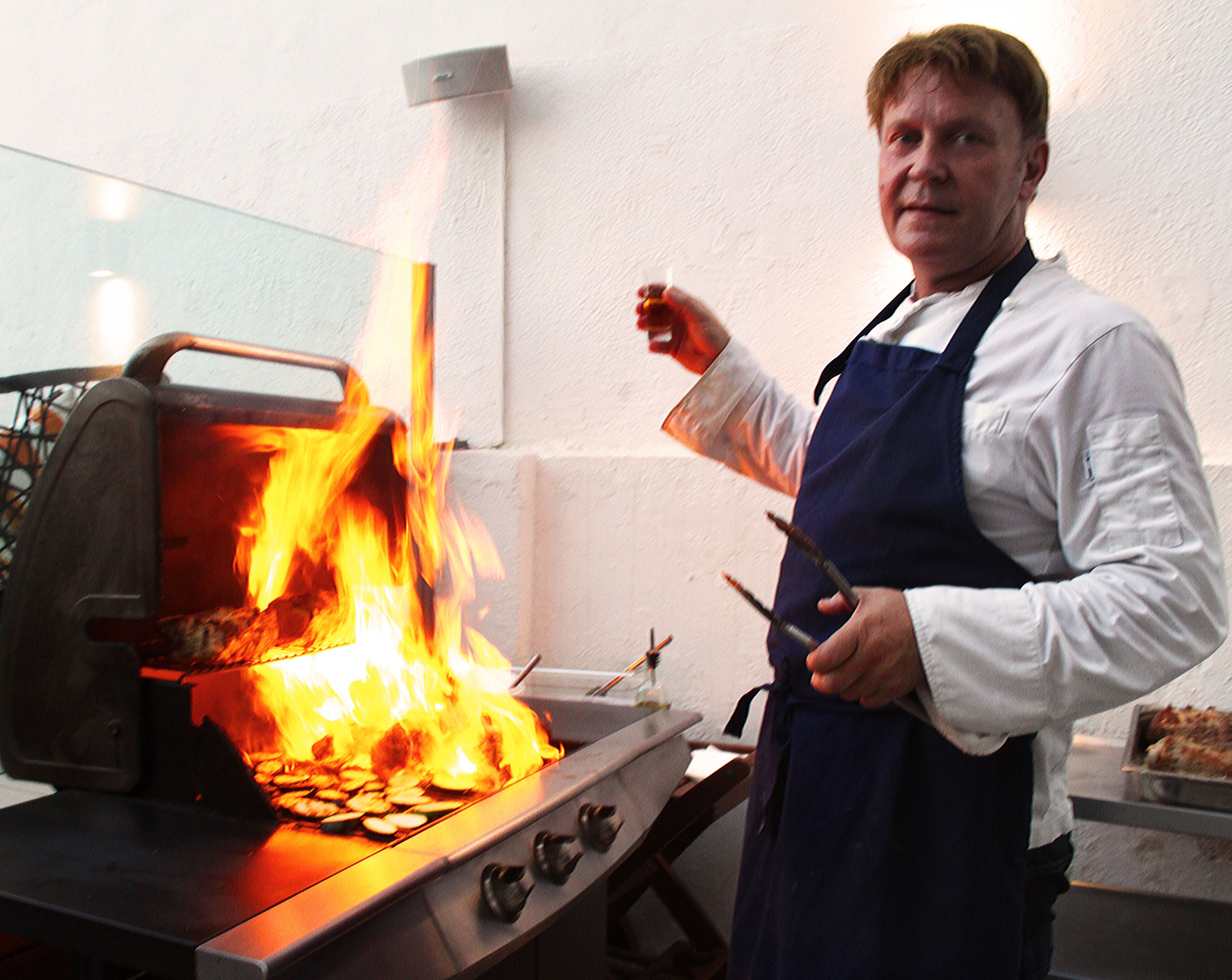 Un chef cuisinant en plein air à l’aide d’un barbecue.