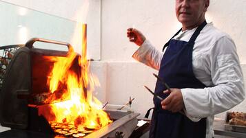 Un chef cuisinant en plein air à l’aide d’un barbecue.