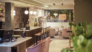 A modern hotel lobby with a marble reception desk, bar area, seating with cushioned chairs, and a view of the city through large windows. - Hotel Feliz (Palma de Mallorca)