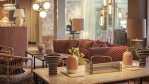 A modern living room with a sofa, dining table, wicker chairs, and hanging light fixtures. - Hotel Feliz (Palma de Mallorca)