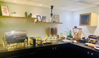 A breakfast buffet with various food items, a coffee machine, and decorative plants.