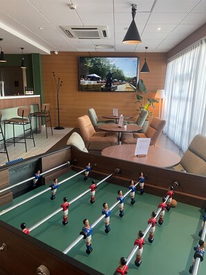 A hotel lobby with a foosball table, seating area, and a television mounted on the wall. - Campanile - Dijon Centre Clemenceau (Dijon)