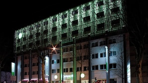 Ein Hotel mit moderner Fassade, mehreren Etagen und beleuchteter Beschilderung.