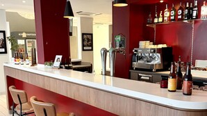 Eine Bar mit Theke, Hockstühlen und einer Kaffeemaschine.