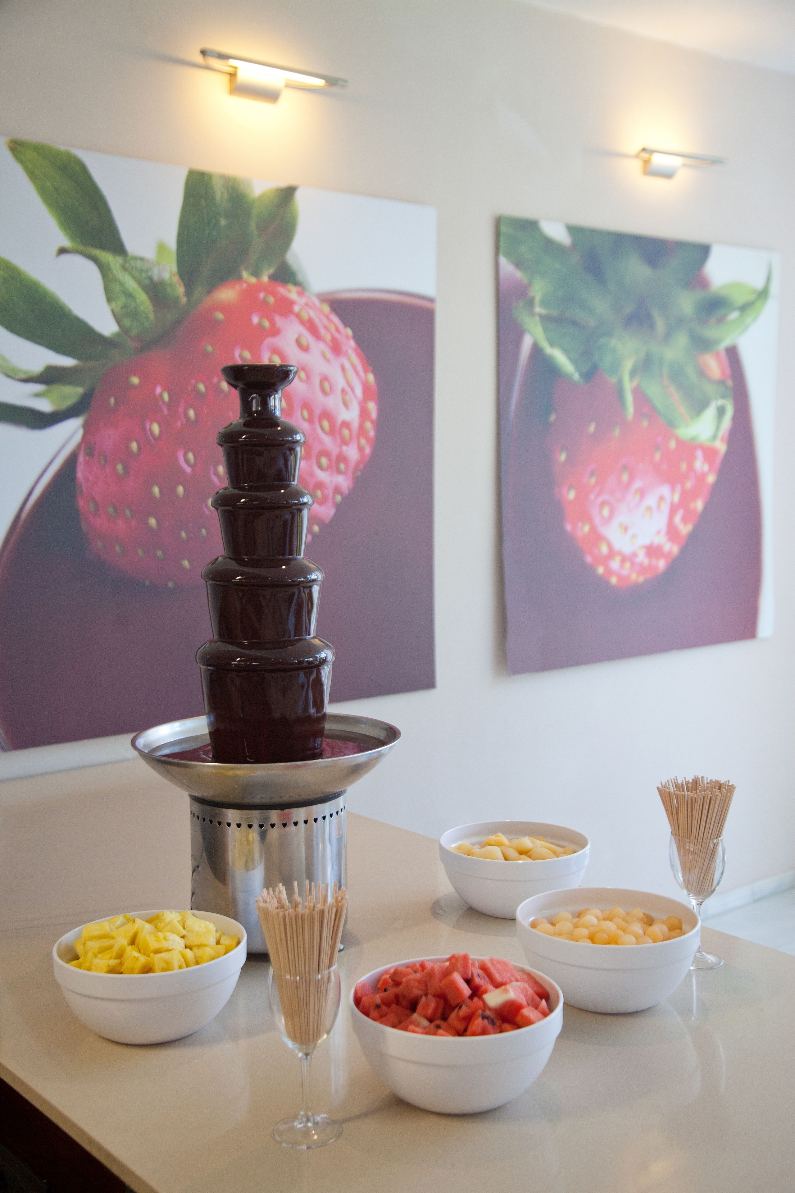 En chokladfontän med olika frukter och ett glas champagne på ett bord.
