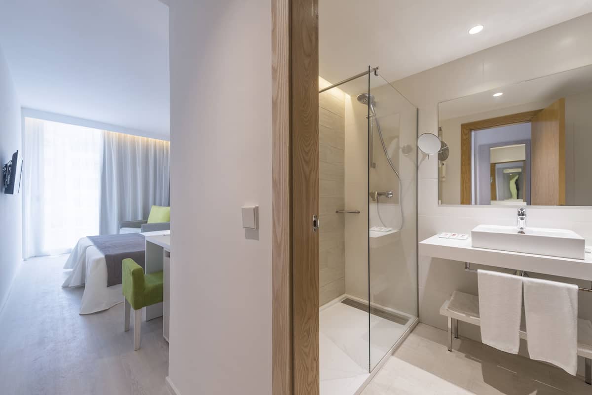 A modern bathroom with a glass shower enclosure, a white sink, and a mirror above it.