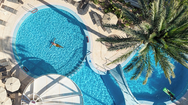 A large outdoor swimming pool with multiple sections, surrounded by lounge chairs and umbrellas. - Hotel JS Sol de Alcudia (Alcúdia)