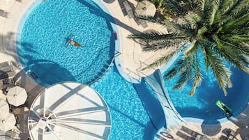 Una piscina al aire libre, sombrillas, sillones reclinables de piscina