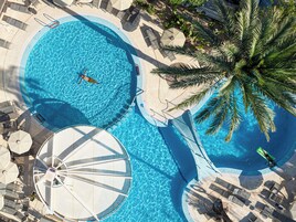 Una piscina al aire libre, sombrillas, sillones reclinables de piscina