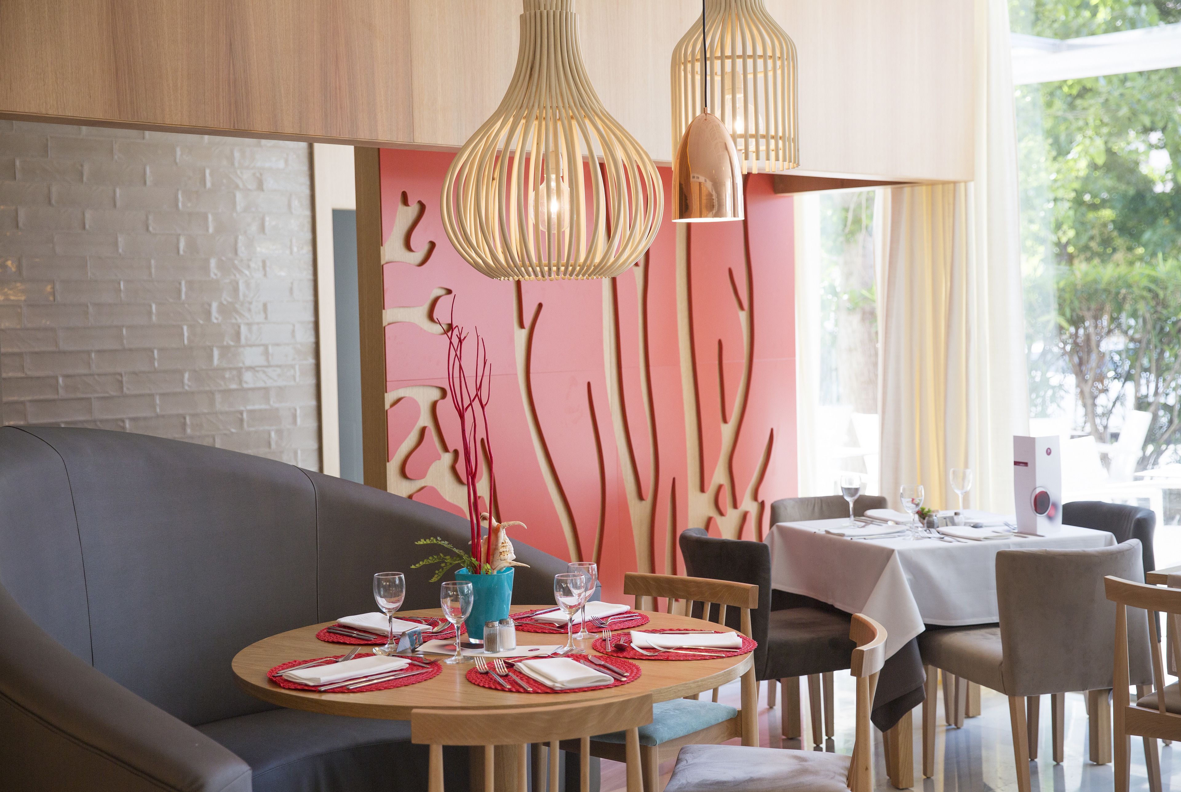 Un comedor con una mesa redonda dispuesta para dos personas, un sofá gris y una pared decorada con arte abstracto.
