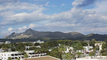 Un pueblo costero con edificios modernos, palmeras y una montaña al fondo.